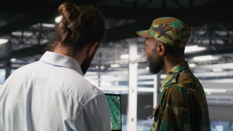 military experts in data center reviewing drone surveillance feed on laptop