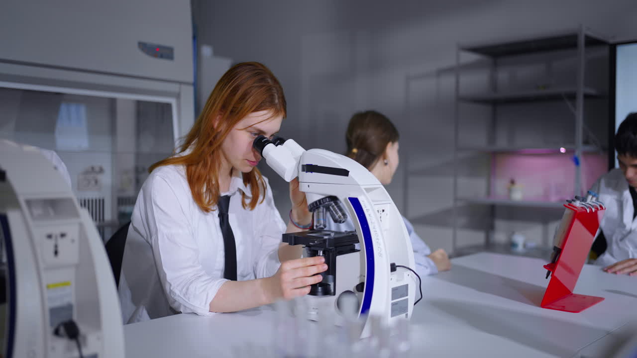mujer joven usando un microscopio en un laboratorio de ciencias
