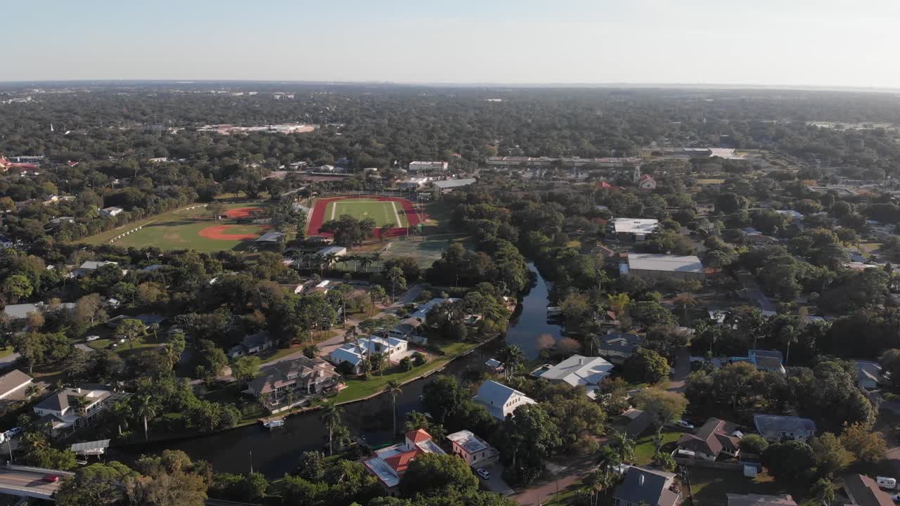 Toma aérea de un barrio tropical de Florida con un campo de fútbol cerca de un bayou.