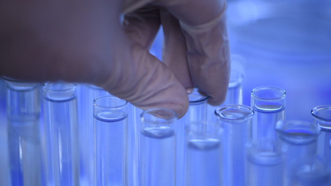 Close-up of Gloved Hand Placing Test Tube with Purple Liquid in Lab