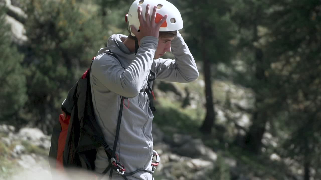 Slow motion shot of young man putting on and tightening helmet before paragliding