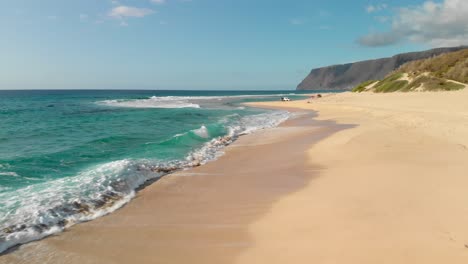 version one. low forward aerial shot over beautiful waves crashing on golden secluded beach in polihale state park, hawaii.