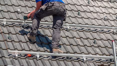 close-up shot van mannelijke arbeider die industriële constructie op het dak voorbereidt met boor voor zonnepanelen