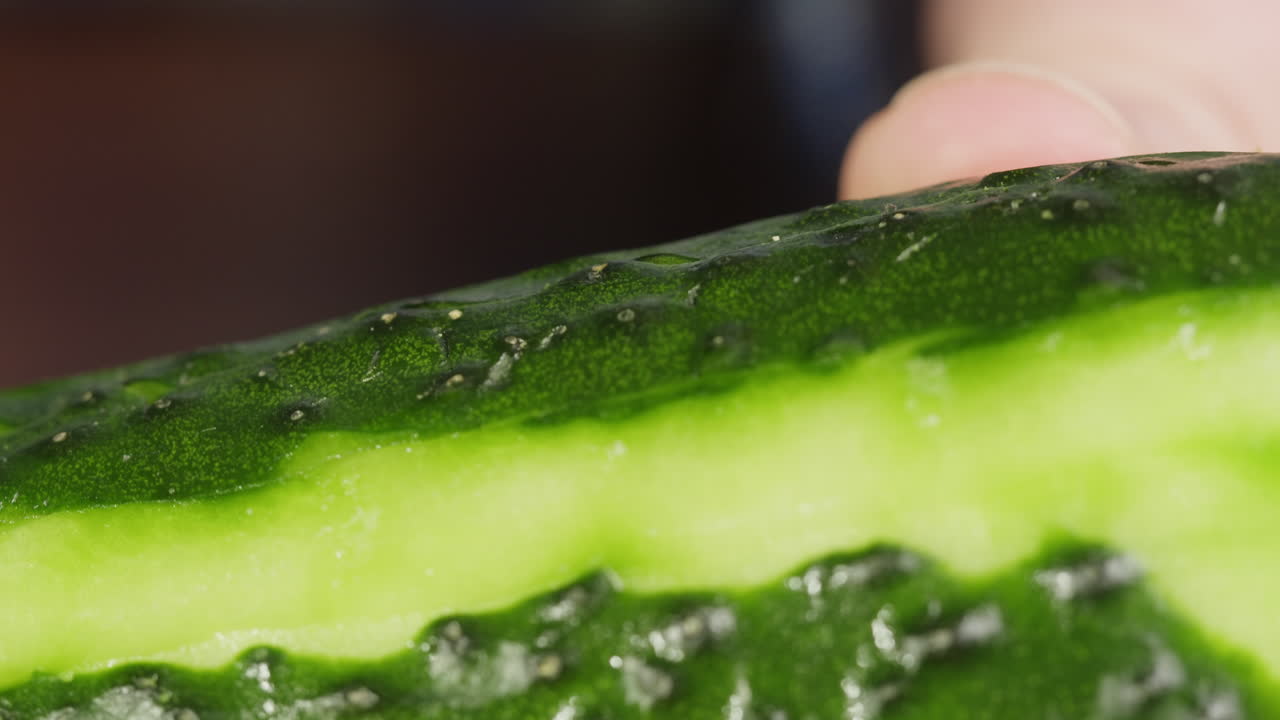 Close-up of a Hand Peeling a Fresh Green Cucumber