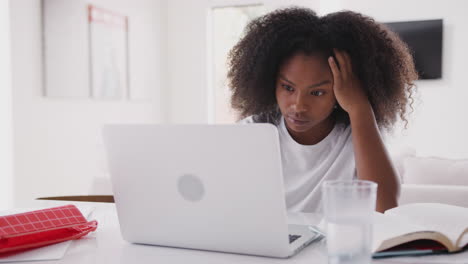 young teenage black girl using laptop computer at home, close up