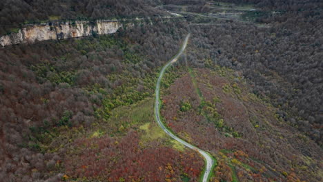 aerial view of winding mountain road through autumn forest