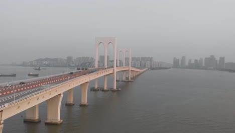 rising and forward moving aerial shot of sai van bridge in macau with taipa skyline in distance