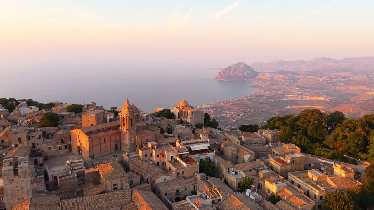 Erice Village With Ancient Church Overlooking The Mount Cofano And Calm Sea At Sunset In Sicily, Italy. - aerial shot