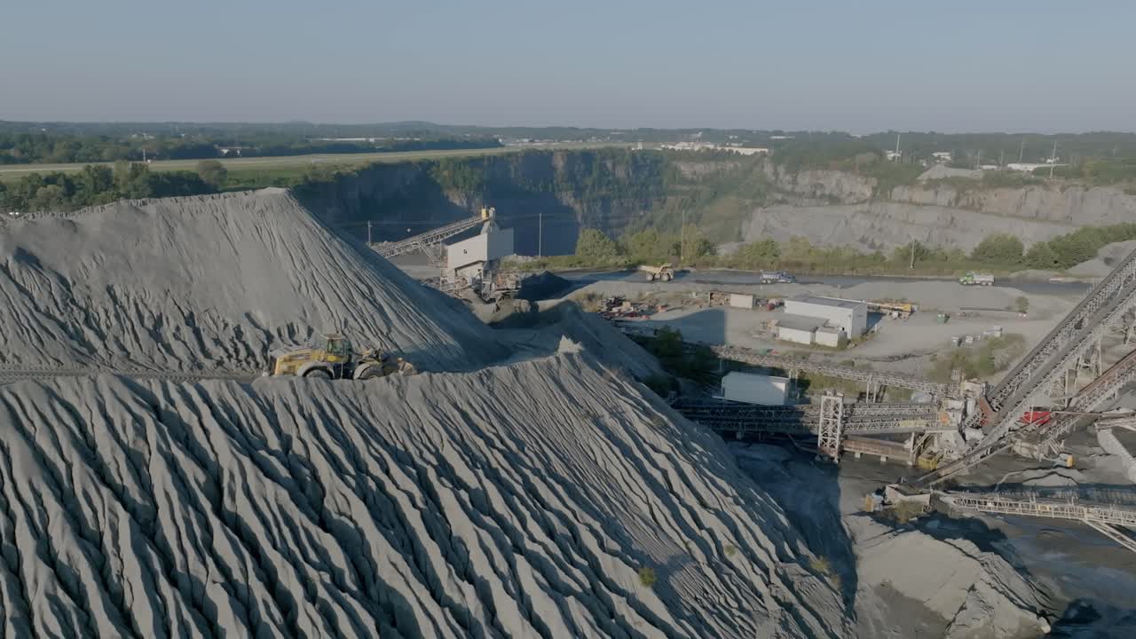 бульдозер движется по дороге, проложенной по внешней стороне холма из гравия