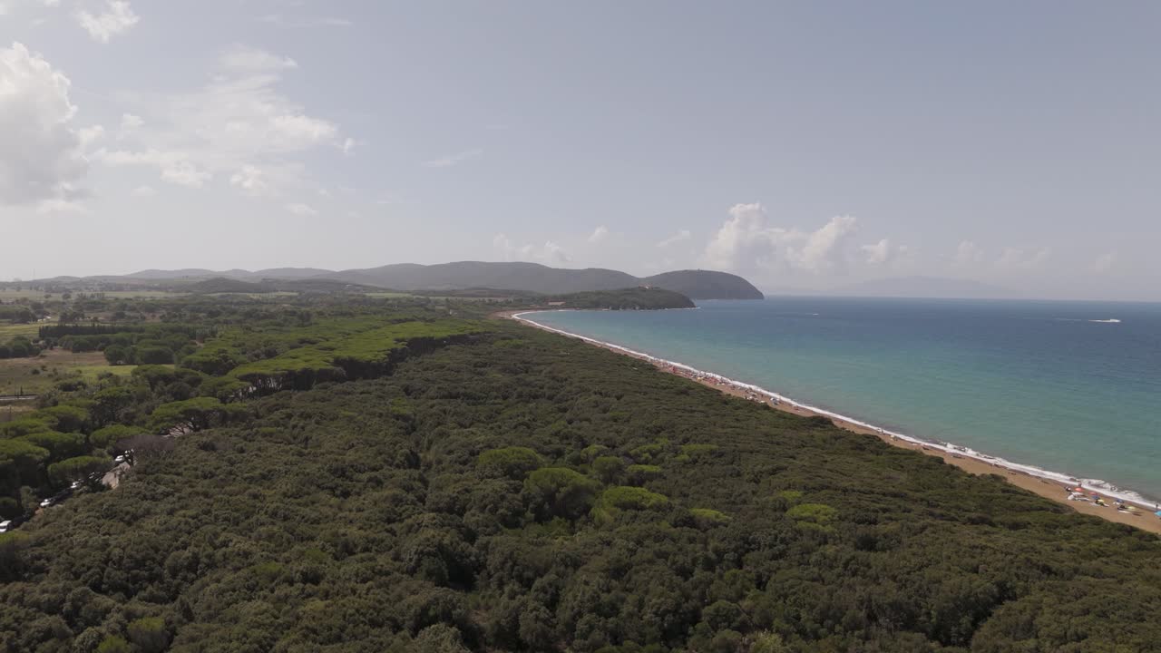 Filmato aereo con drone della spiaggia di Spiaggia in Toscana, che mostra una lunga costa sabbiosa, acqua turchese, foresta costiera e dolci colline. Ideale per produzioni a tema viaggi, estate, Mediterraneo e natura.