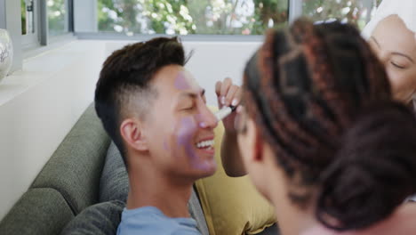 young asian man enjoys a playful moment at home applying a face mask