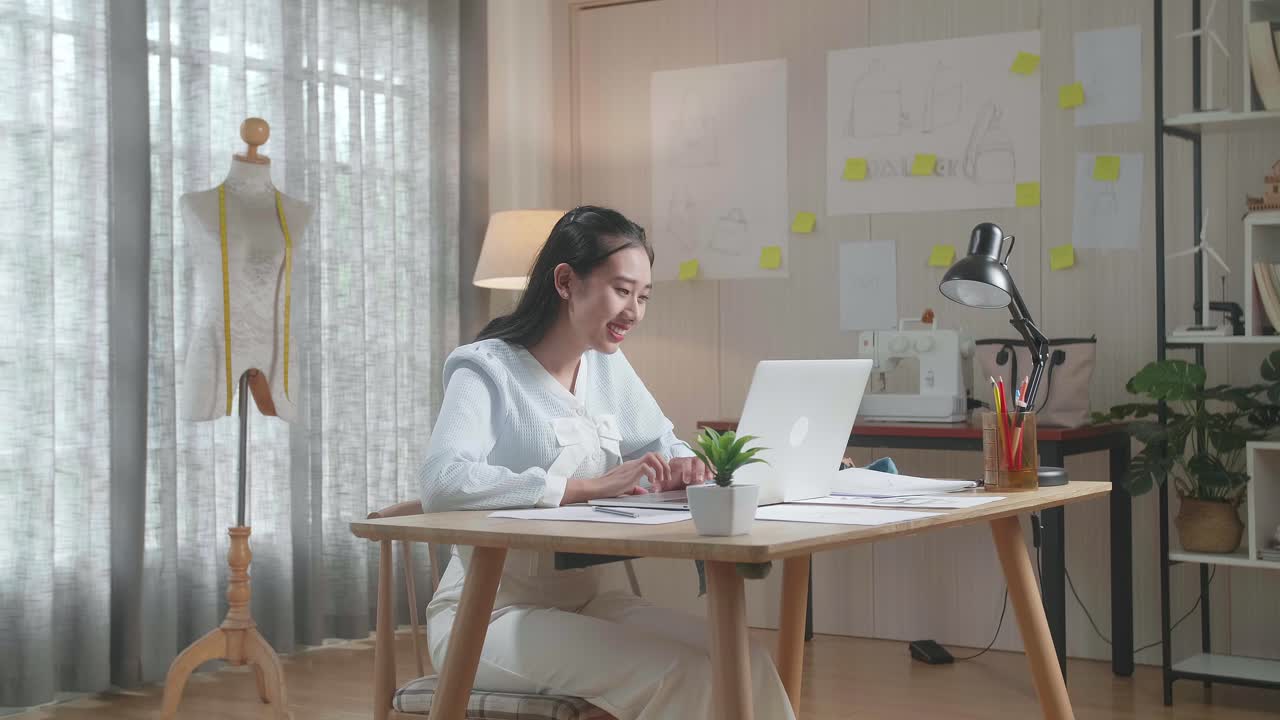 사무실에서 노트북을 사용하여 레이아웃 본드를 가진 아시아 여성 가방 디자이너