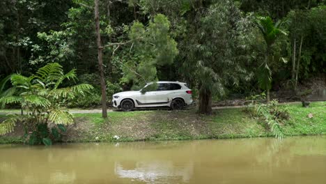 kuala lumpur, malaysia - march 9, 2022: brand new car 2020 bmw x5 wheelhouse interior. concept of luxury. hybrid cars. white bmw x5 suv driving down the road with a river in the foreground.