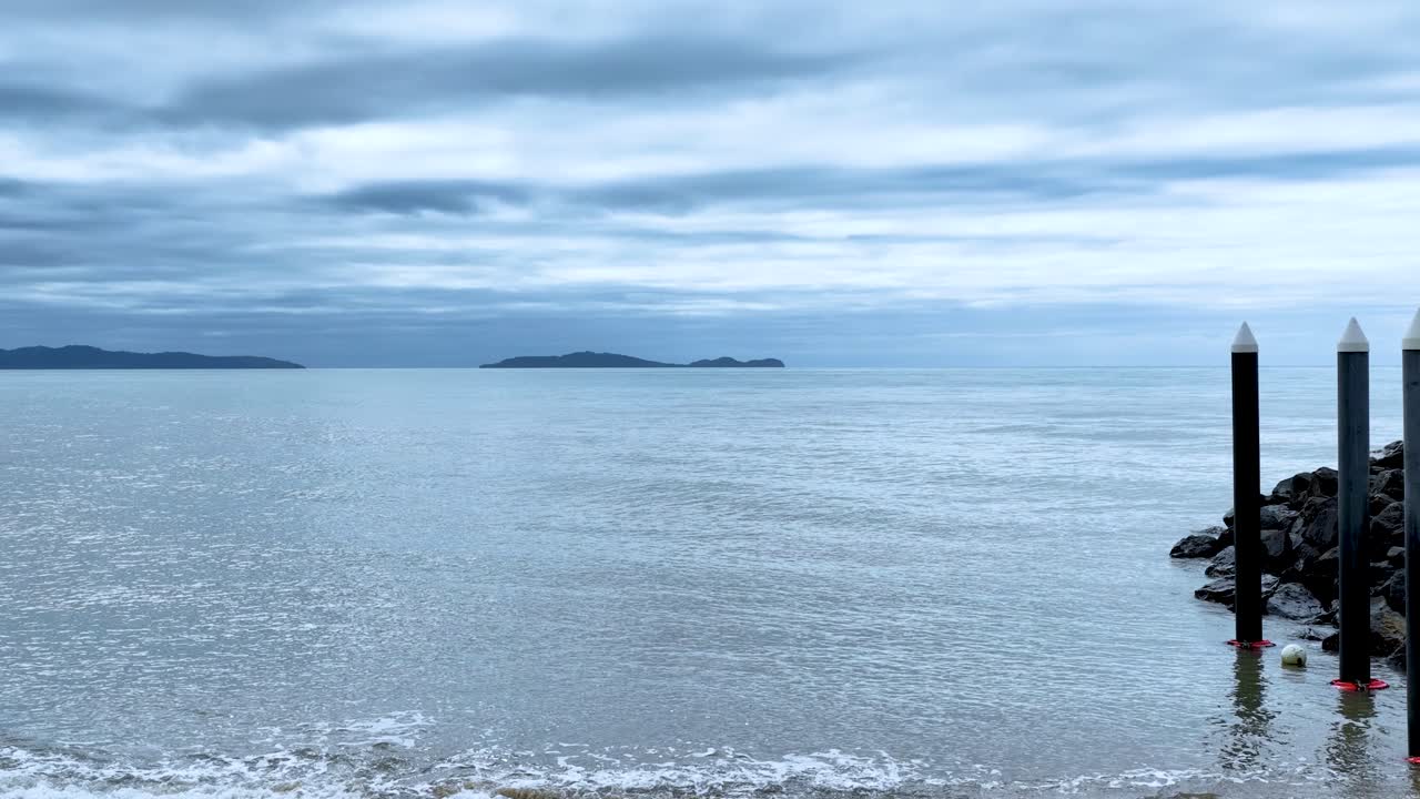 Camera slowly pans from boat ramp to tranquil ocean under cloudy sky, soft natural lighting