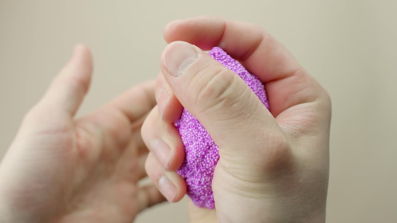 Close-up of pink Floam slime being kneaded for ASMR, set against a calm beige background.