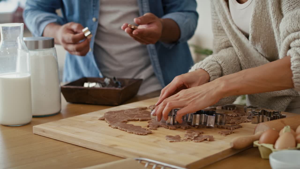 Close up of multi ethnicity couple making a gingerbreads in Christmas time .