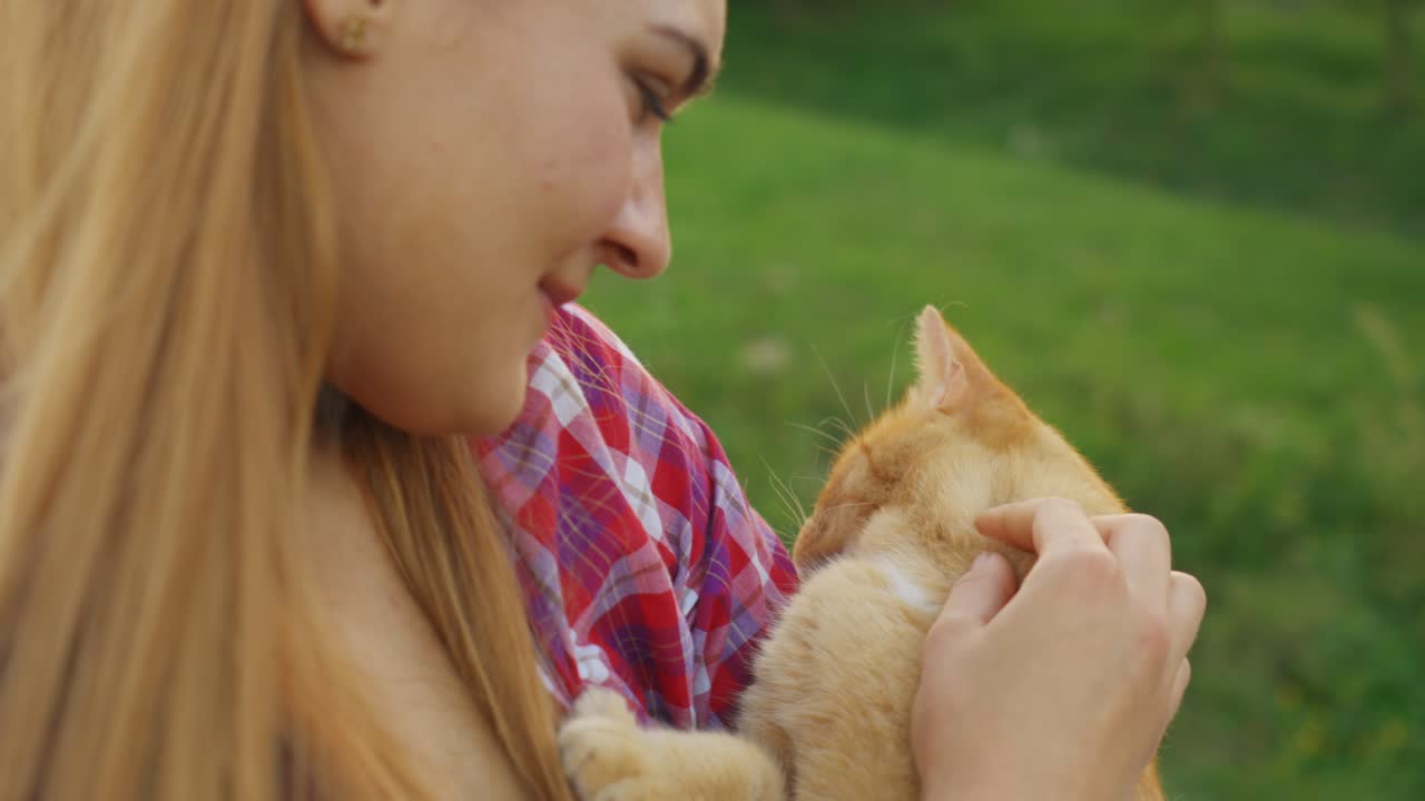 Young Caucasian woman gently holding and cuddling an orange cat in warm cinematic lighting, showing love, affection, and the bond between humans and pets in a cozy, intimate atmosphere