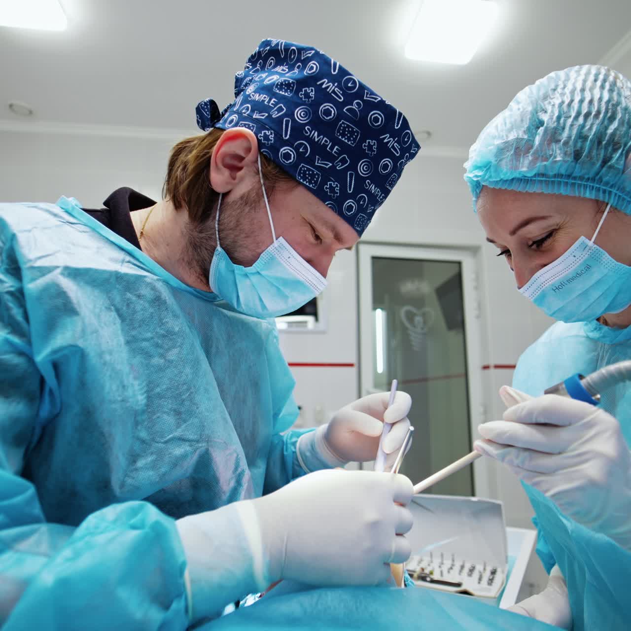 Dentist assisted by a nurse performs teeth care procedure. Doctor uses metal tools and nurse holds the saliva ejector