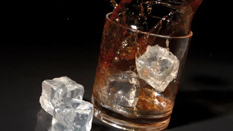 Ice-cubes-falling-into-tumbler-of-whiskey-and-ice-