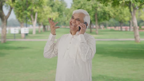 Happy-Indian-old-man-talking-on-phone-in-park