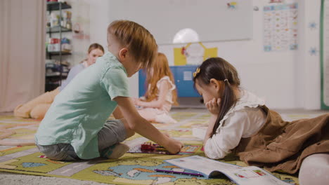 niña y niño jugando con diferentes piezas en la alfombra en el aula en una escuela montessori 1