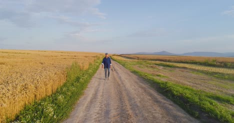 investigador agrícola masculino de pie en un camino de tierra en medio de los campos 2