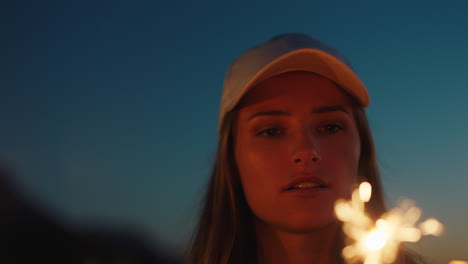 woman playing with sparklers on beach at sunset enjoying new years eve celebration looking at firework sparks girl celebrating independence day