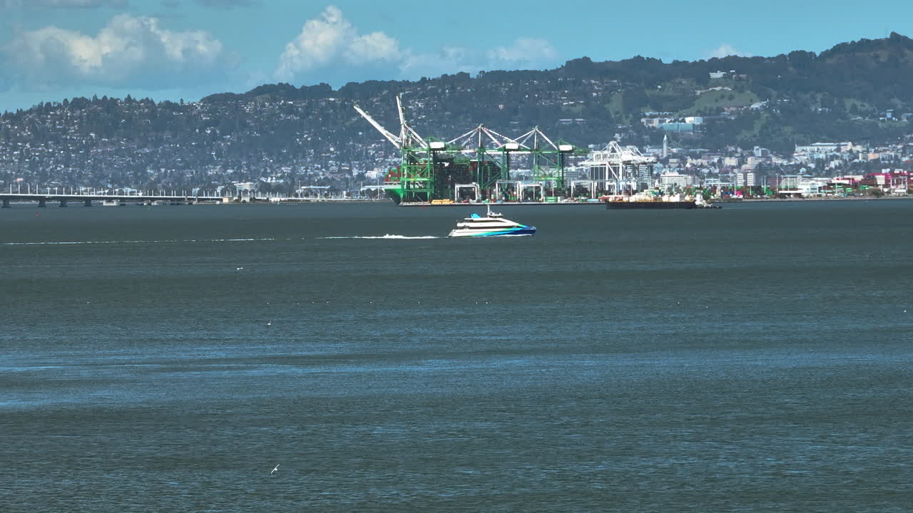 Telephoto aerial of a yacht on the bay with Oakland backdrop, in sunny California