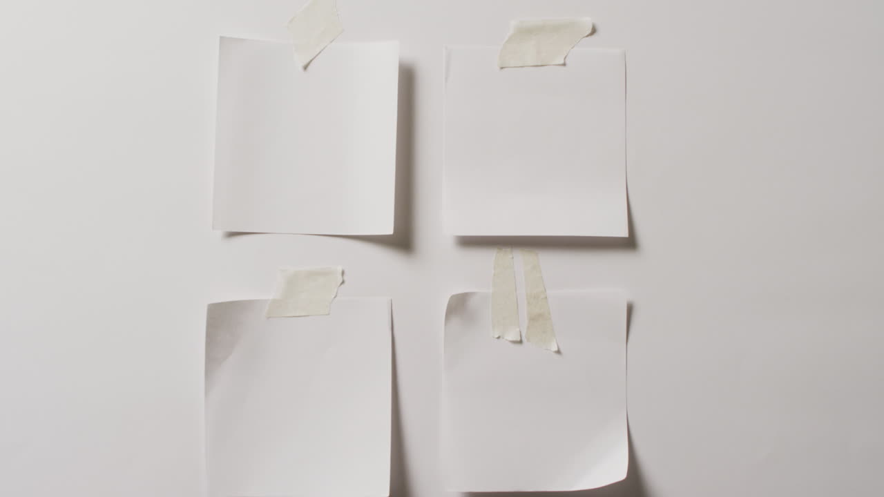 Video of close up of four white memo notes with copy space taped to white background