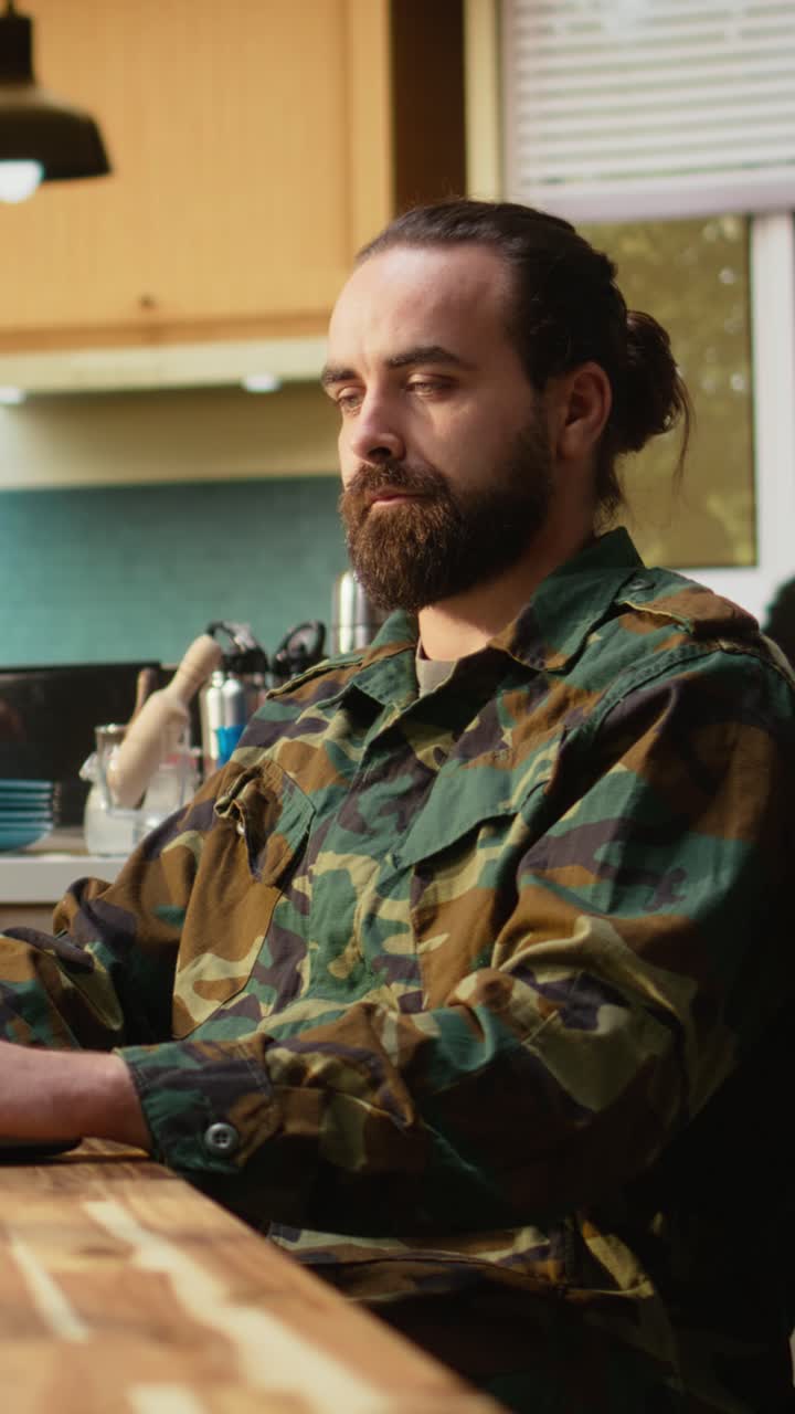 Vertical Video Off duty serviceman in military uniform with laptop and coffee at home