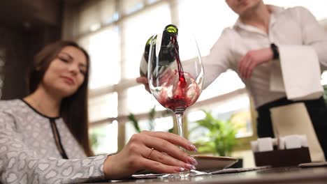 woman being served red wine in a restaurant
