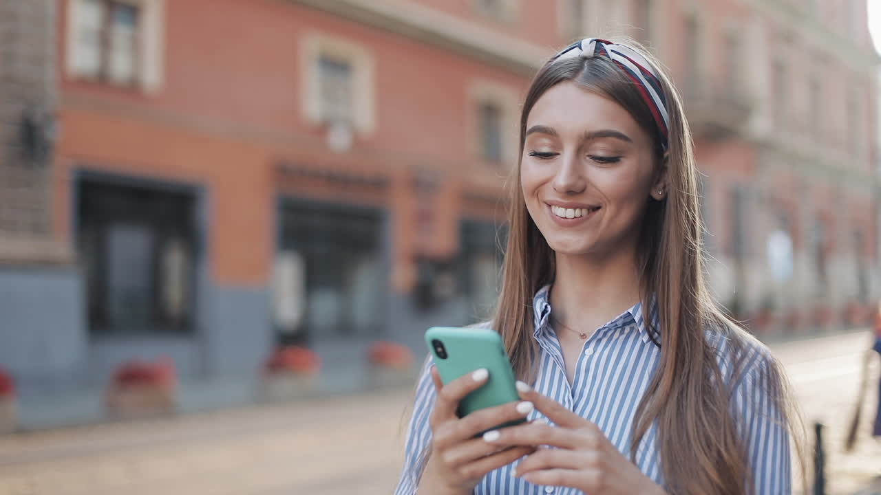 Giovane donna felice che usa lo smartphone in una strada cittadina