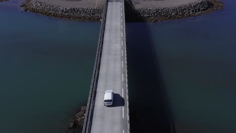 white car crossing bridge over calm river mouth at iceland coastal land, aerial