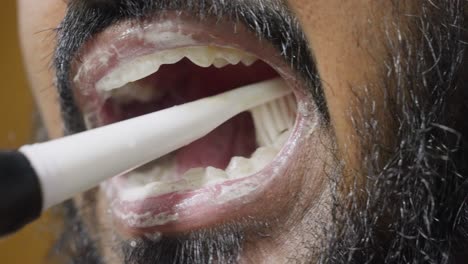 a slow-motion, close-up footage of a south asian man brushing his teeth, with a blurred background. dental care and hygiene concept