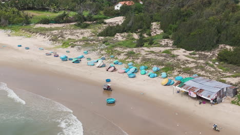 drone shot of coracle boats lining the beach as waves crash in mui ne vietnam