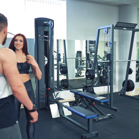 sportive couple come into fitness center. beautiful woman and athlete man in sports wear go to their daily training on the background of modern gym.