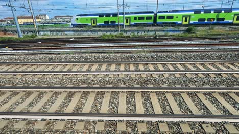 green train moves swiftly across multiple tracks