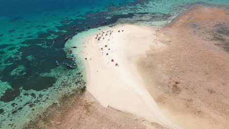 sandy spit on a coral reef with tourists and boats