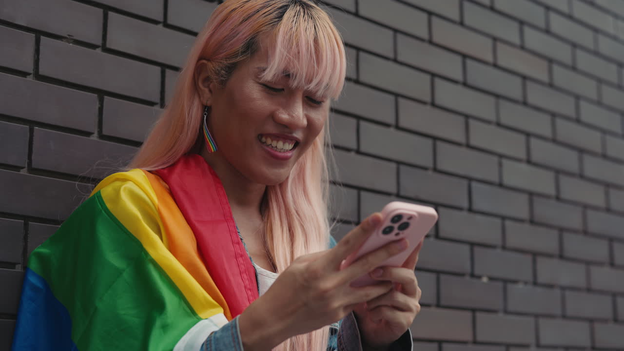 Frau mit Handy und Regenbogenflagge