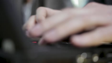 Hands-typing-on-a-laptop-keyboard,-focus-on-fingers,-in-an-office-setting