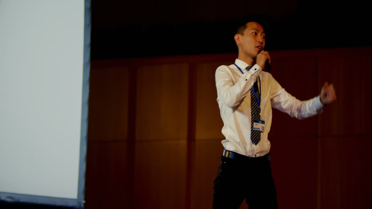 Giovane uomo d'affari asiatico che parla a un seminario aziendale in un auditorium 4k