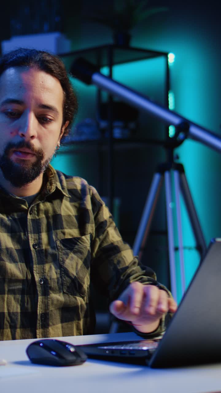 Emprendedor grabando un vídeo vertical trabajando desde casa, usando un portátil y escribiendo notas en papel