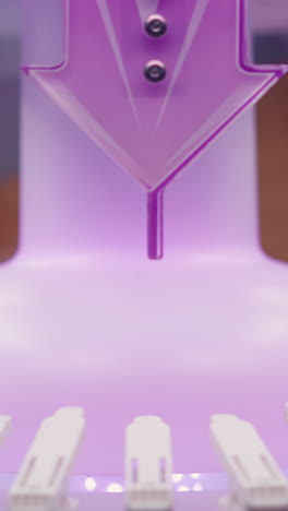 primer plano de un objeto iluminado púrpura girando con detalles de diseño intrincados en una configuración de máquina moderna, la estructura circundante incluye componentes blancos y luz brillante suave