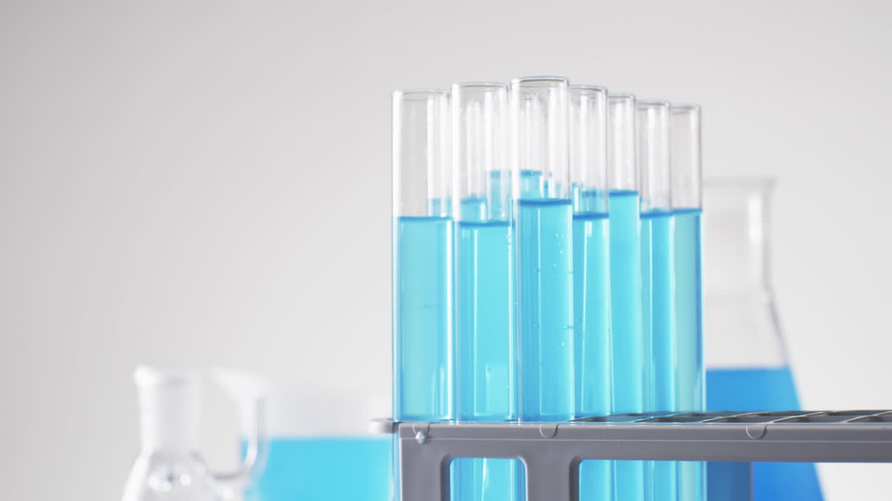 Video of glass laboratory test tubes with blue liquid with copy space on white background