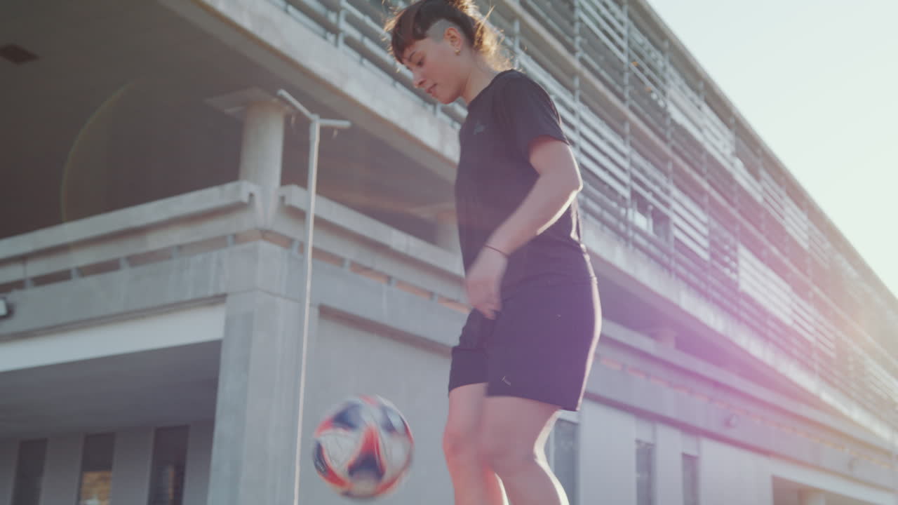 Young Woman Doing Kick-Ups with Soccer Ball on the Street