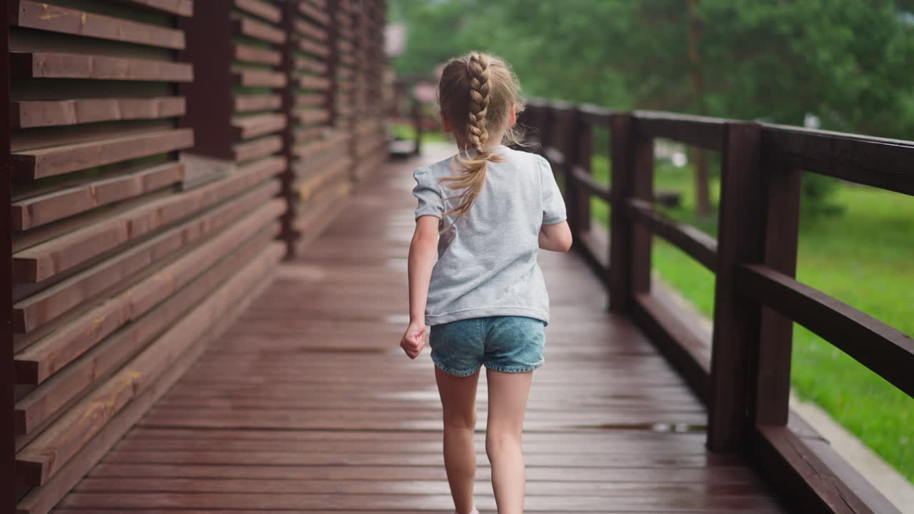 una niña con trenzas rubias corre a lo largo de la terraza vacía