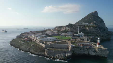 Eine-Wunderbare-Hochfliegende-Drohnenaufnahme,-Die-Den-Südlichsten-Punkt-Gibraltars-Bei-Sonnenuntergang-Mit-Einer-Einzigen-Wolke-Darüber-Und-Dem-Meer-Auf-Beiden-Seiten-Zeigt