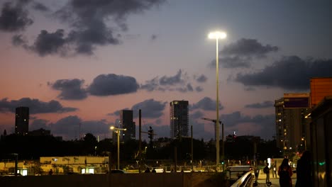 car traffic and pedestrians on the streets of tel aviv in the evening, establishing shot