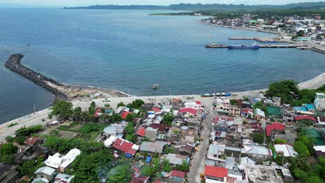 establishing aerial view of beachfront community facing pristine sea waters with harbors and a lone rock breakwater