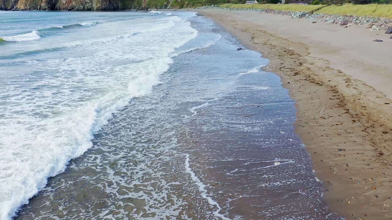 Vista aerea di onde che si infrangono su una tranquilla spiaggia sabbiosa nel sud dell'Irlanda in estate.